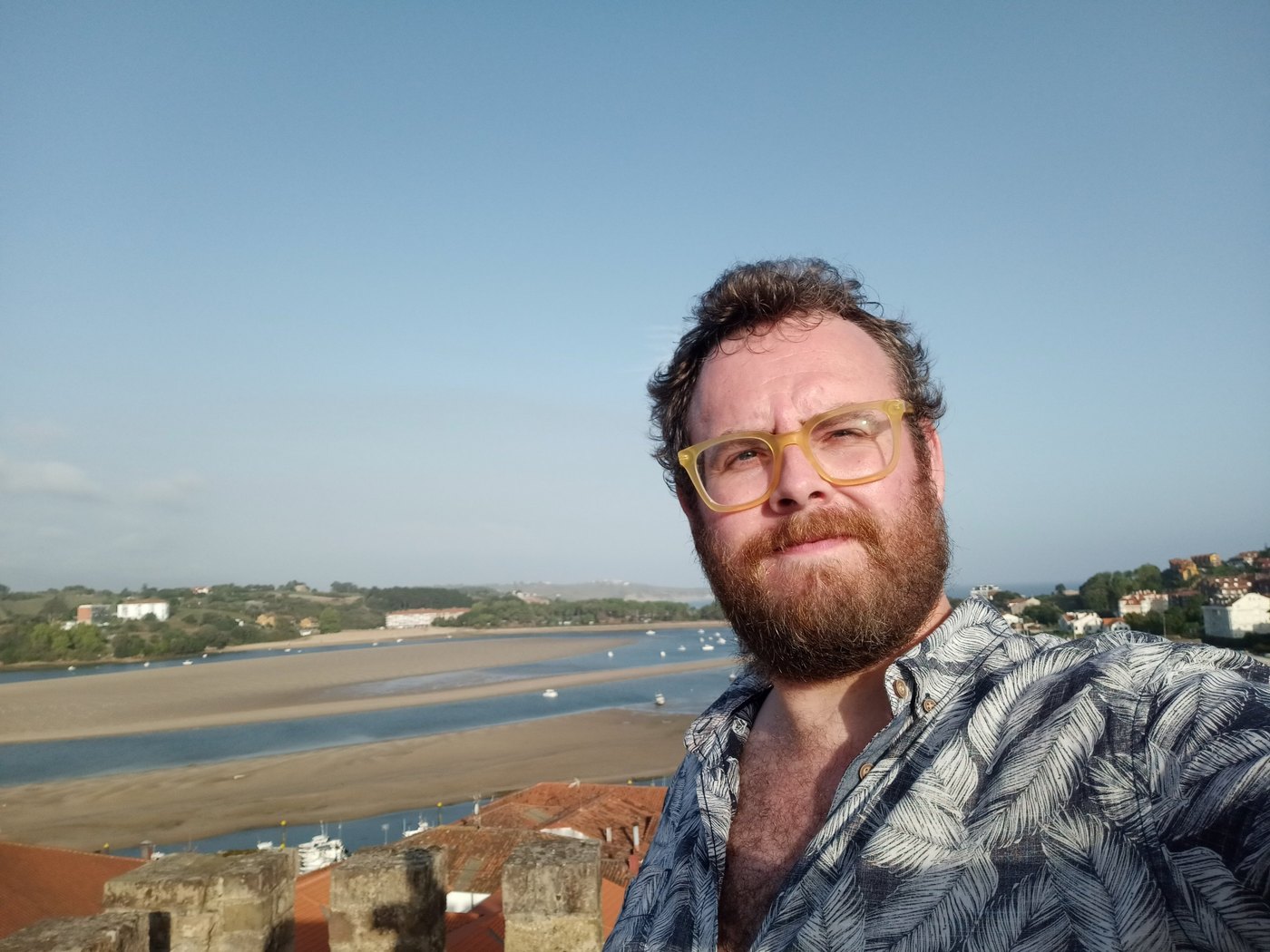 Tristan Hotham in yellow glasses on castle walls above an estuary